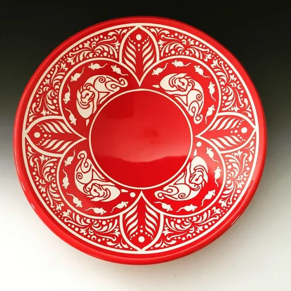 A red bowl with white designs on it.