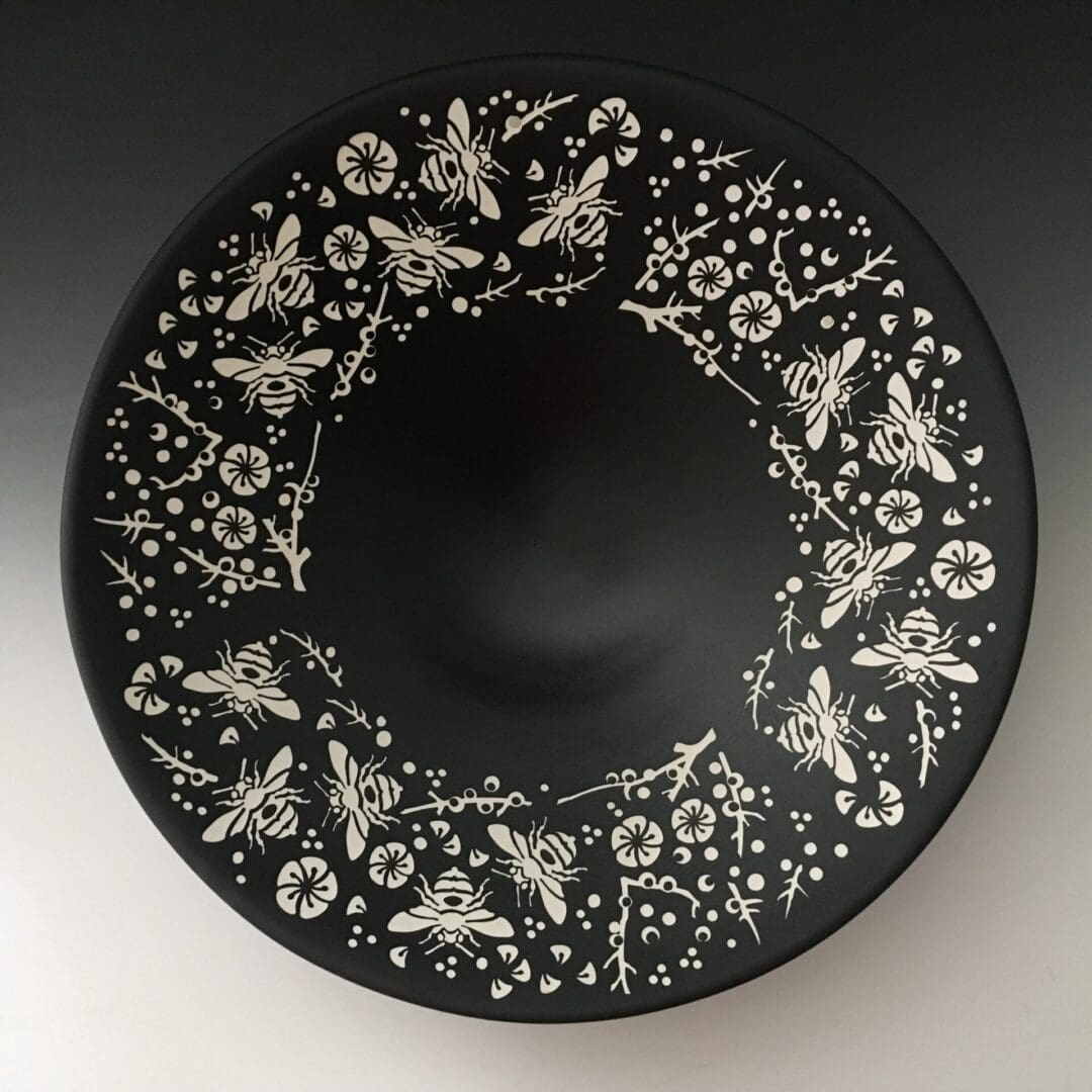 A black plate with white flowers and butterflies.