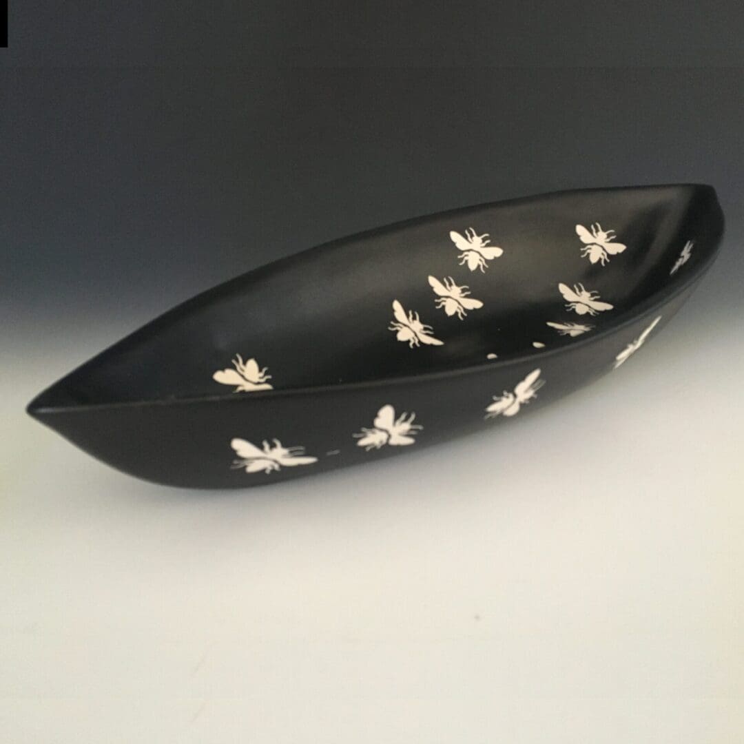 A black bowl with white bees on it.