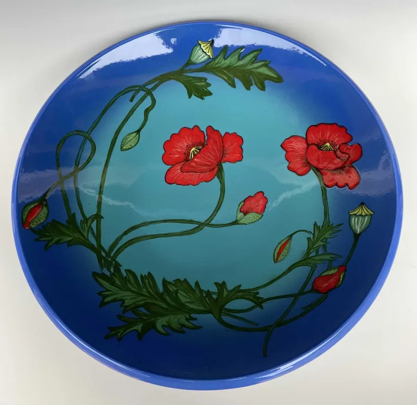 A blue bowl with red flowers on it.