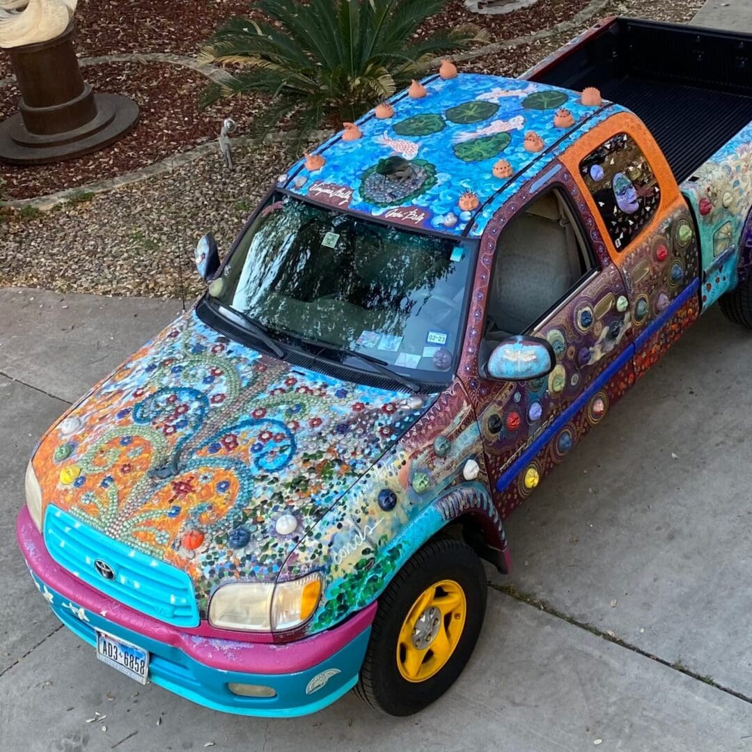 A colorful truck parked in the driveway of a house.